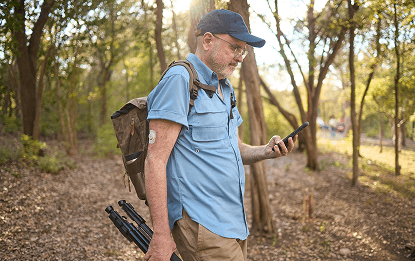 Man hiking while checking his glucose levels with the Dexcom CGM